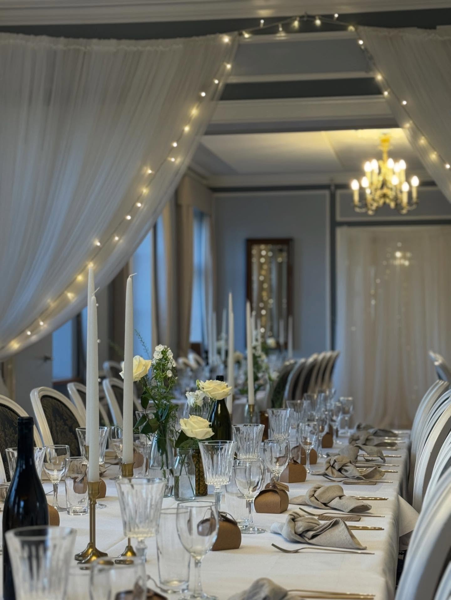 Elegant bordopsætning med lysekroner, kertelys og blomster til selskab